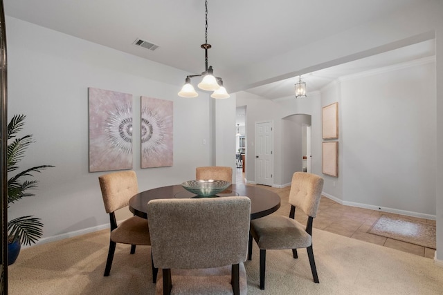 dining area featuring crown molding, arched walkways, baseboards, and visible vents