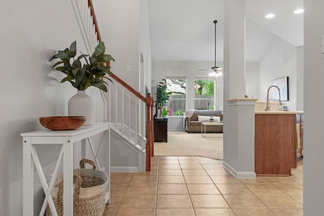 entrance foyer with stairs, baseboards, light colored carpet, a ceiling fan, and light tile patterned floors