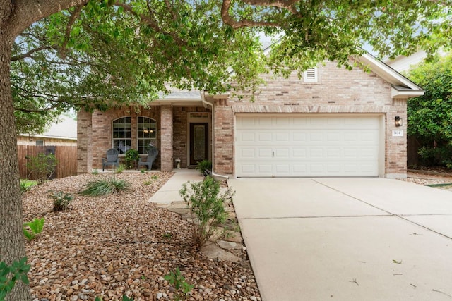 view of property hidden behind natural elements with fence, a garage, driveway, and brick siding