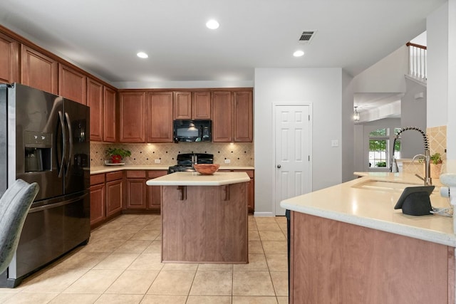kitchen featuring black microwave, gas stove, light countertops, fridge with ice dispenser, and visible vents