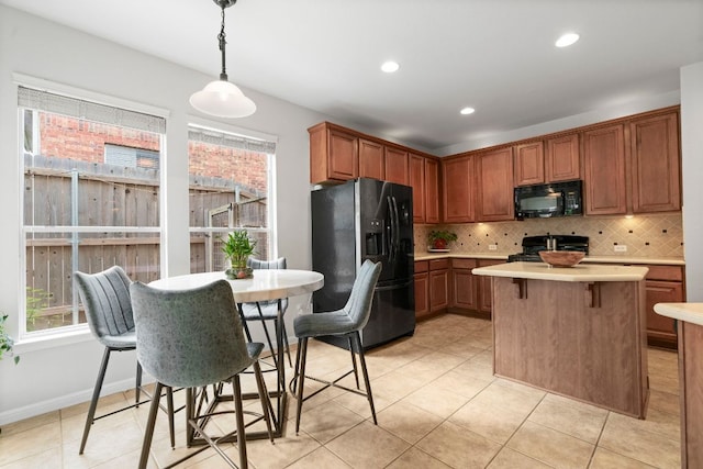kitchen with light countertops, tasteful backsplash, black appliances, and a healthy amount of sunlight