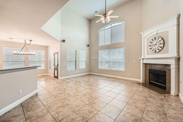 404 Scarlet Maple Dr, Cedar Park, TX 78613 - unfurnished living room with a tiled fireplace, light tile patterned floors, baseboards, ceiling fan with notable chandelier, and a high ceiling