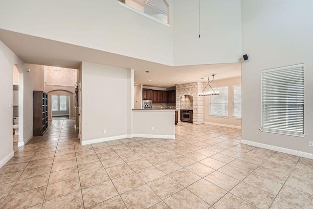 404 Scarlet Maple Dr, Cedar Park, TX 78613 - unfurnished living room with a brick fireplace, arched walkways, a high ceiling, and light tile patterned floors