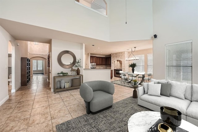 404 Scarlet Maple Dr, Cedar Park, TX 78613 - living room with a towering ceiling, arched walkways, a fireplace, light tile patterned floors, and baseboards