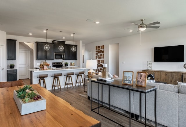 living room featuring a ceiling fan, recessed lighting, and wood finished floors