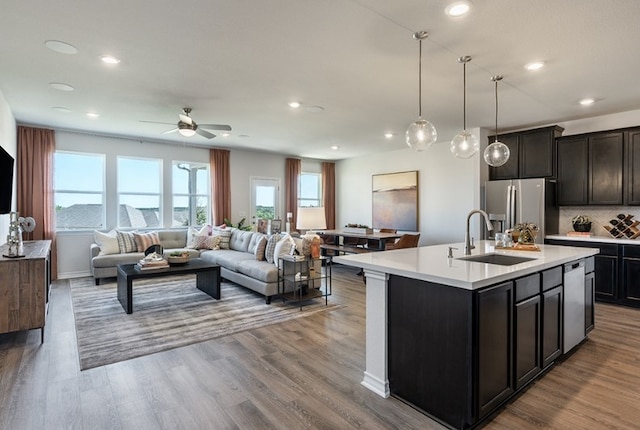 kitchen featuring ceiling fan, a sink, light countertops, stainless steel appliances, and open floor plan