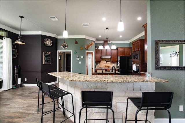 1066 Vista Dr, Salado, TX 76571 - kitchen with stainless steel appliances, under cabinet range hood, crown molding, a peninsula, and light stone counters