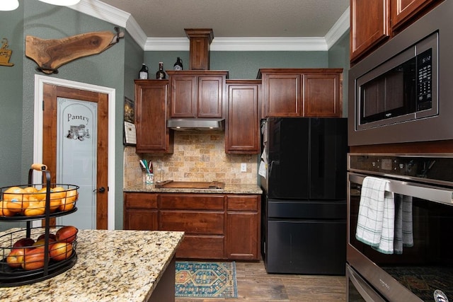 1066 Vista Dr, Salado, TX 76571 - kitchen featuring appliances with stainless steel finishes, under cabinet range hood, ornamental molding, wood finished floors, and decorative backsplash