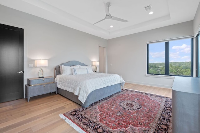 bedroom featuring ceiling fan, visible vents, light wood-style floors, a tray ceiling, and recessed lighting