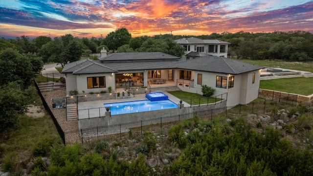 back of property with a fenced backyard, stucco siding, and a tile roof