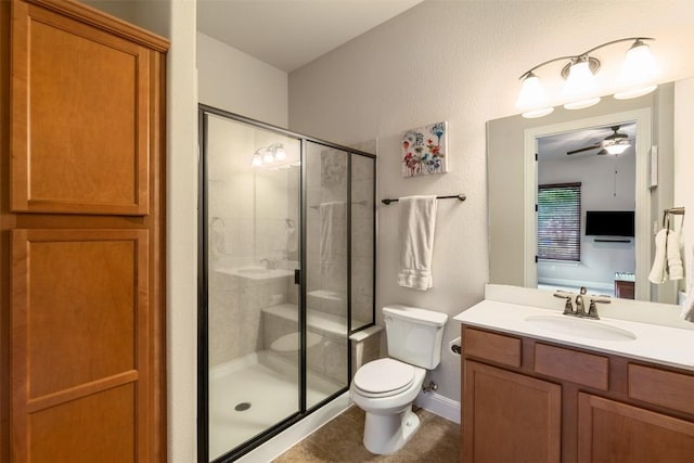 bathroom with vanity, toilet, baseboards, a ceiling fan, and a stall shower