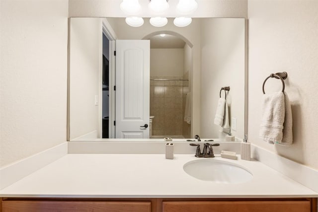 full bath with tiled shower and vanity