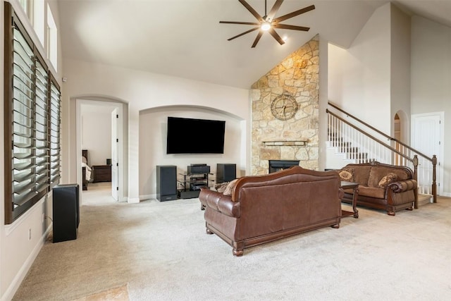 2917 Windy Vane Dr, Pflugerville, TX 78660 - living area featuring a ceiling fan, carpet flooring, a stone fireplace, arched walkways, and high vaulted ceiling