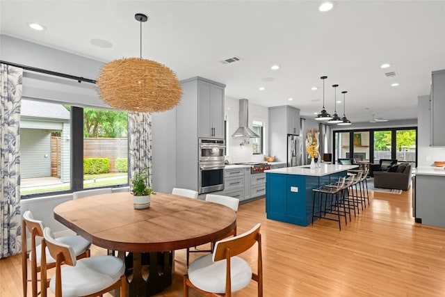 interior space with wall chimney range hood, appliances with stainless steel finishes, gray cabinets, and visible vents