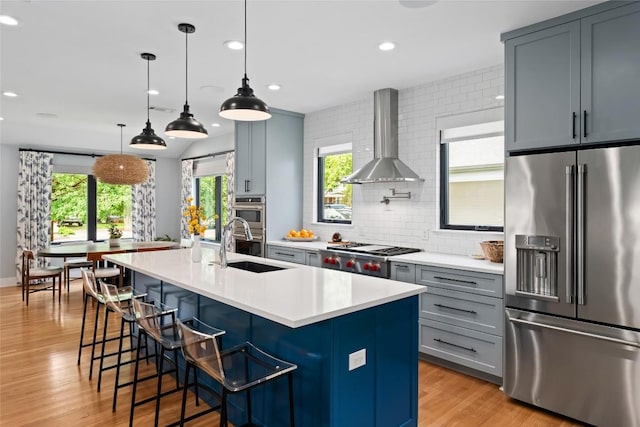 kitchen with recessed lighting, light countertops, wall chimney exhaust hood, backsplash, and stainless steel appliances