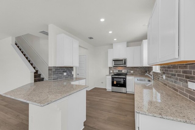 200 Lucky Texan Rd, Jarrell, TX 76537 - kitchen with stainless steel appliances, a peninsula, decorative backsplash, light stone countertops, and light wood-style flooring