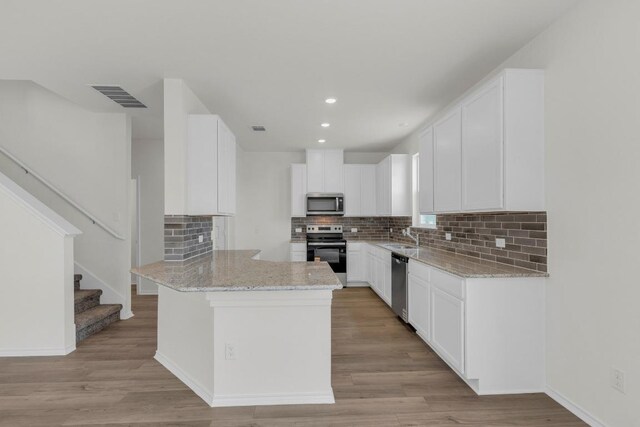 200 Lucky Texan Rd, Jarrell, TX 76537 - kitchen with appliances with stainless steel finishes, a peninsula, light stone countertops, recessed lighting, and decorative backsplash