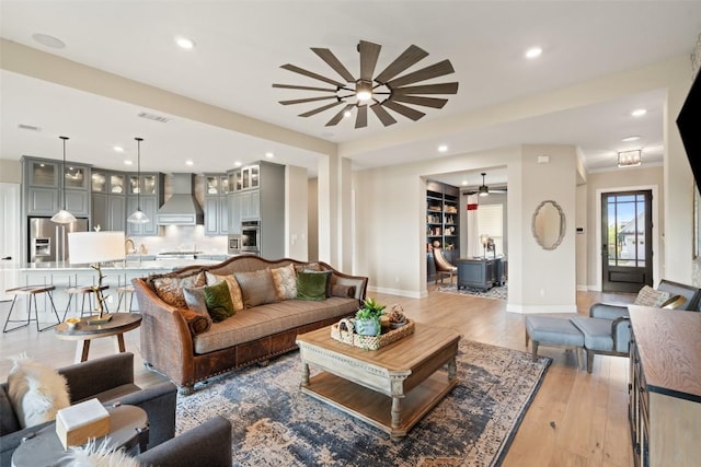 living room with light wood finished floors, a ceiling fan, baseboards, recessed lighting, and visible vents