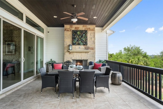 balcony with an outdoor stone fireplace, a ceiling fan, and outdoor dining area