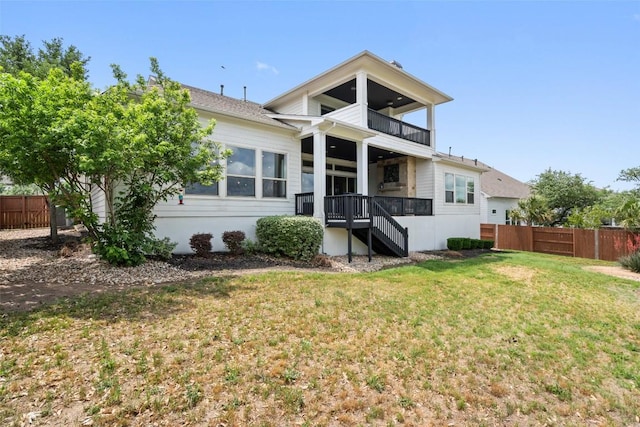 rear view of property with a lawn, fence, and a balcony