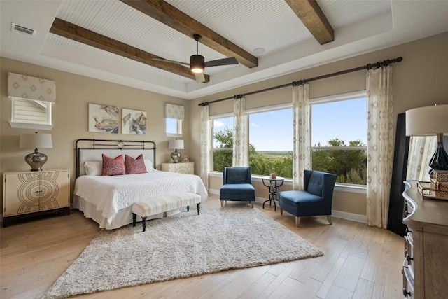 bedroom with multiple windows, light wood-type flooring, and beam ceiling