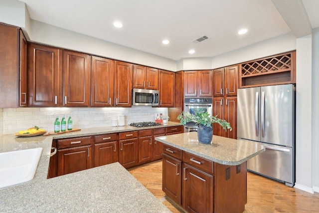 300 San Gabriel Village Blvd Unit 721, Georgetown, TX 78626 - kitchen featuring appliances with stainless steel finishes, decorative backsplash, light wood finished floors, open shelves, and recessed lighting