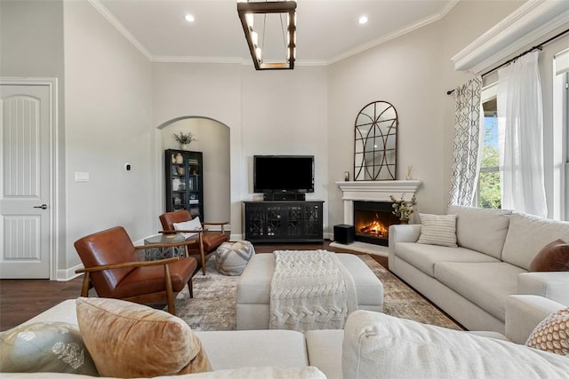 living room with crown molding, recessed lighting, wood finished floors, and a warm lit fireplace