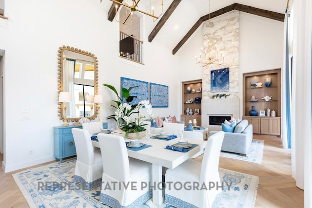 dining area with baseboards, high vaulted ceiling, a chandelier, built in shelves, and a large fireplace