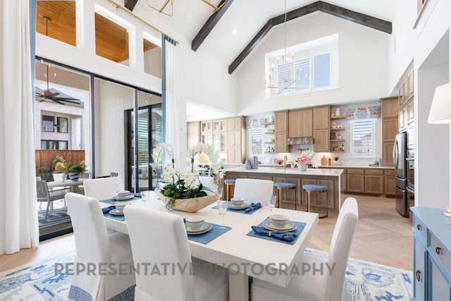 dining space with ceiling fan with notable chandelier, beam ceiling, and high vaulted ceiling