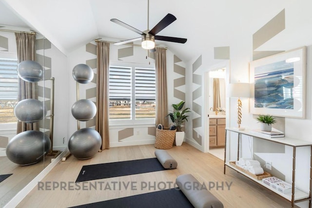 exercise area with light wood-type flooring, a ceiling fan, baseboards, and vaulted ceiling