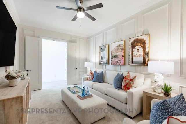 living room featuring ornamental molding, a decorative wall, ceiling fan, and light colored carpet