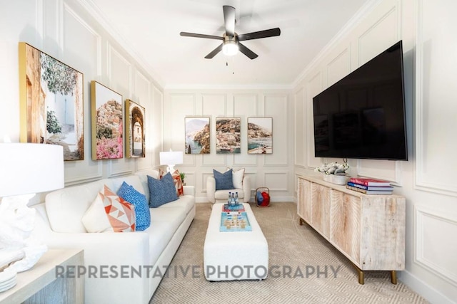 living area with light colored carpet, ornamental molding, ceiling fan, and a decorative wall