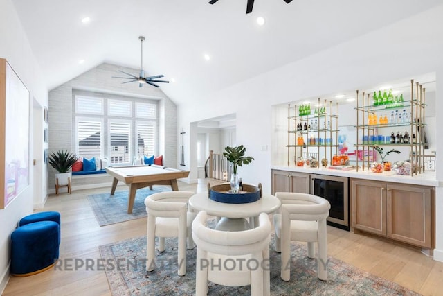 interior space featuring light wood-style floors, indoor wet bar, a ceiling fan, wine cooler, and vaulted ceiling