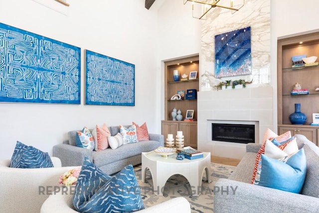 living room featuring built in features, a chandelier, and a tile fireplace