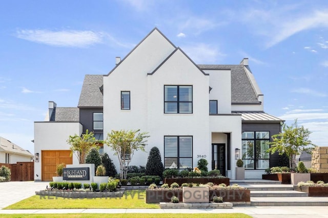 view of front of home with fence, decorative driveway, a standing seam roof, metal roof, and an attached garage
