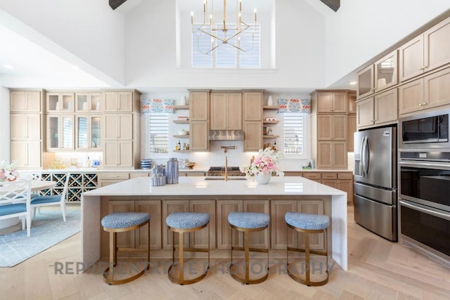 kitchen with open shelves, light countertops, a breakfast bar area, stainless steel appliances, and a towering ceiling