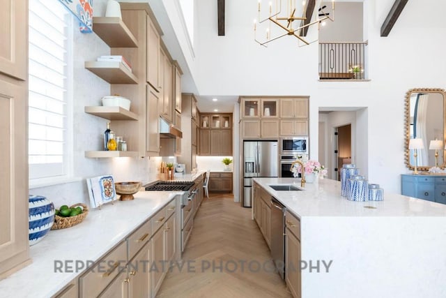 kitchen with a large island, open shelves, a sink, under cabinet range hood, and stainless steel appliances