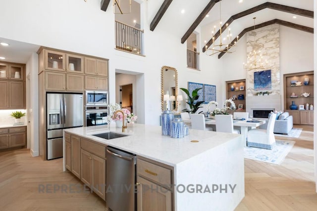 kitchen featuring open floor plan, high vaulted ceiling, a chandelier, a sink, and stainless steel appliances