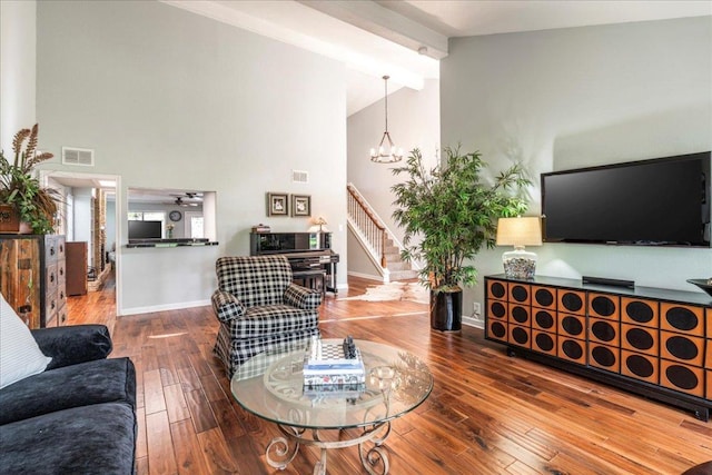 living area with beam ceiling, wood-type flooring, a chandelier, baseboards, and visible vents