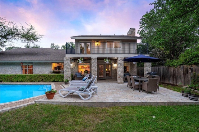 10601 Spicewood Pkwy, Austin, TX 78750 - back of house at dusk featuring a balcony, a patio area, a chimney, and french doors
