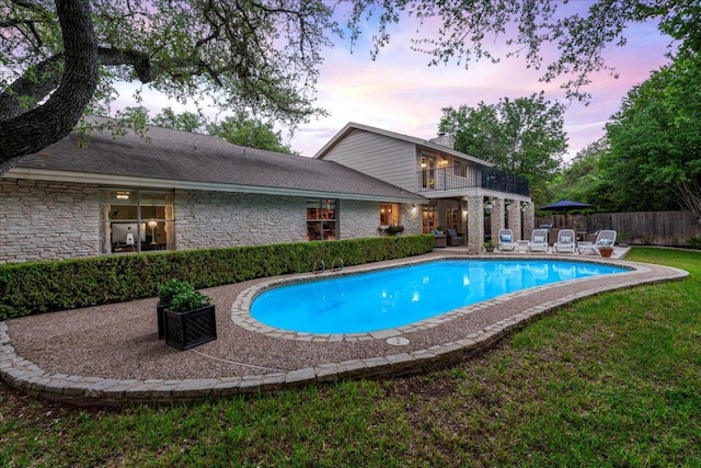 pool at dusk with fence, a fenced in pool, a yard, and a patio area
