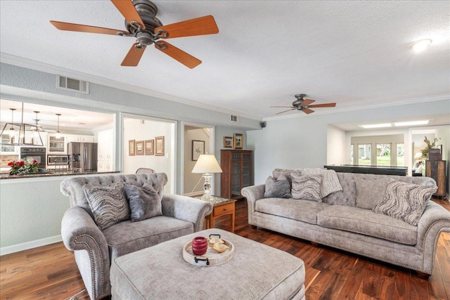living area featuring ceiling fan, visible vents, crown molding, wood finished floors, and baseboards