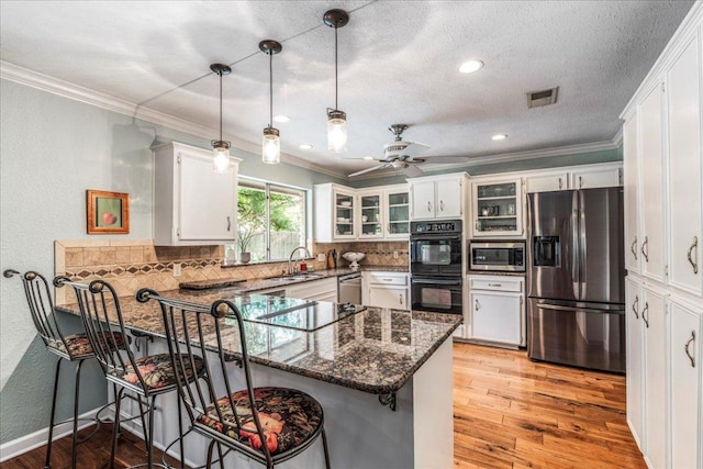 10601 Spicewood Pkwy, Austin, TX 78750 - kitchen featuring black appliances, a peninsula, a sink, tasteful backsplash, and glass insert cabinets