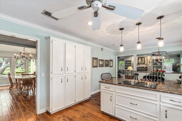 kitchen featuring black electric cooktop, ceiling fan with notable chandelier, white cabinetry, dark wood-type flooring, and visible vents