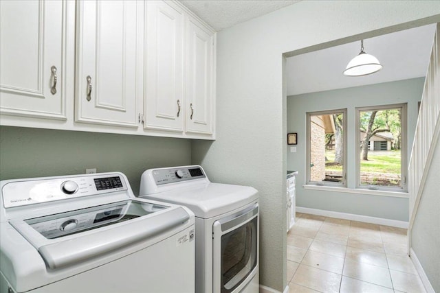 laundry area with cabinet space, baseboards, washing machine and dryer, and light tile patterned floors