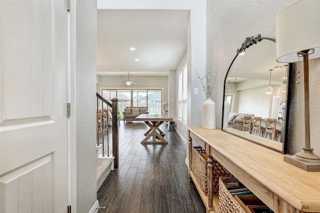 hall with dark wood-style flooring, a textured wall, and recessed lighting