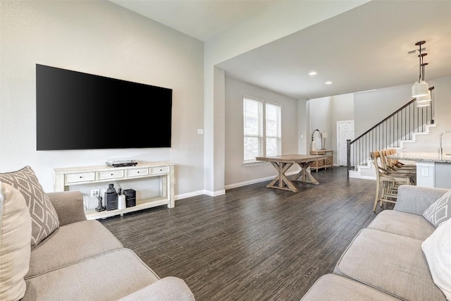 living area with dark wood finished floors, baseboards, recessed lighting, and stairs