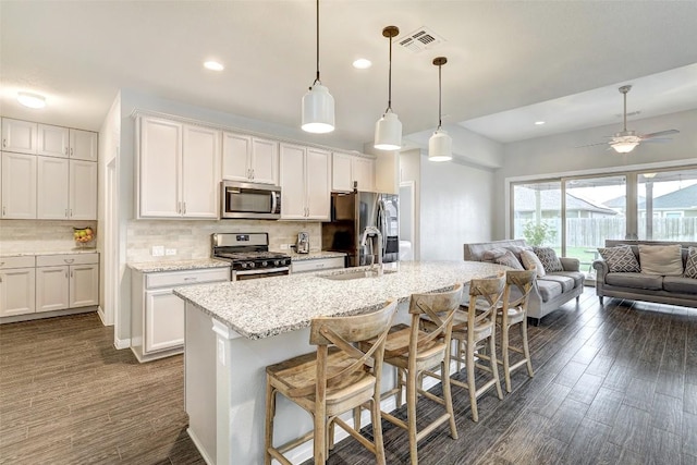 kitchen with stainless steel appliances, open floor plan, visible vents, and a sink