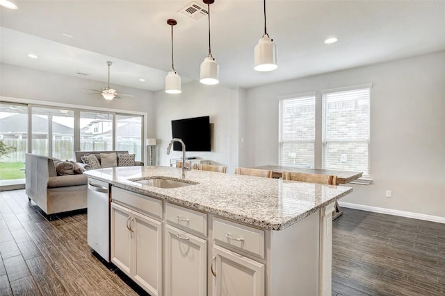kitchen featuring stainless steel dishwasher, visible vents, a sink, and dark wood-type flooring