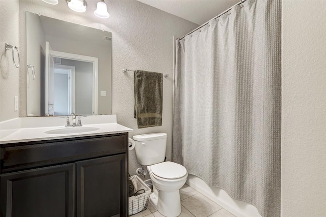 bathroom featuring toilet, a textured wall, tile patterned floors, and vanity